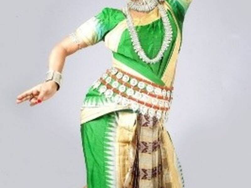 Eine Person in traditioneller indischer Tanzkleidung führt eine elegante Pose aus.